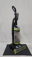 Bissell CleanView Swivel Pet upright vacuum angled to show hose and base with lime green accents and clear dirt container.