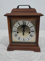 Front view of the Hamilton wooden mantel clock with Roman numerals and floral decorative center.
