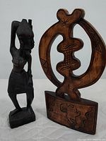Photo showing both hand carved wooden sculptures together: the African tribal woman and the African symbol sculpture.