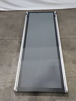 Top-down image showing the full length of the dog ramp with grey textured surface and silver adjustable metal frame sides.