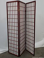 Front view of the three-panel cherry finish room divider with grid patterned white inserts.