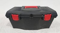 Closed black plastic tool box with red handle and latches