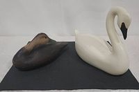 Both wooden fowl decoys displayed side by side on black surface, showing size difference and overall shape.