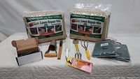 Full lot overview showing two EZ Straw Lawn Repair Mix bags, garden stakes box, three garden hand tools, birdhouse, bird bath brush, two packaged garden weed bags.