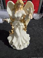Front view of white and gold angel figurine with wings and dove on arm showing detailed face, gown, and gold accents.