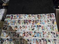 First photo showing approximately half of the 100 baseball cards laid out with player images and team logos.