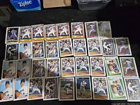 Photo showing 35 Nolan Ryan baseball cards laid out on a black surface, multiple teams and years visible.
