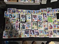 Photo showing multiple 1984 Topps baseball cards arranged on a surface featuring players with team names including Royals, Expos, Reds, and more.