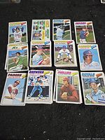 Display of several 1977 Topps baseball cards arranged on a black surface, showing players from various teams in action and portraits.