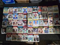 Photo showing a selection of 1986 Topps baseball cards laid out, featuring players from various MLB teams including Royals, White Sox, Blue Jays, Braves, Dodgers, Reds, Cardinals, Astros, Cubs, Brewers, Tigers, Yankees, Indians, Phillies, Padres, Orioles, and Rangers.