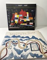 Photo of the two book covers: 'Mapping the World: Stories of Geography' and 'The Map as Art: Contemporary Artists Explore Cartography' showing illustrative map art on each.