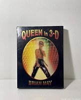 Front cover of the Queen in 3-D book by Brian May showing Freddie Mercury singing on stage.