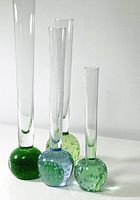 Four vintage Scandinavian bud vases with bubble glass bases in green and blue seen against a white background.