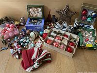 Overview of assortment of vintage Christmas decorations on wooden floor, including baubles, figurines, and festive shaped items