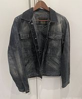 Full front view of the faded denim jean jacket hanging on a hanger, showing button details and pocket design.
