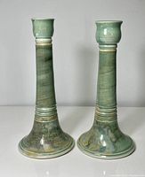 Front view of the pair of pottery candle holders showing differences in height and glaze pattern.