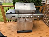 Front view of the Master Chef stainless steel propane gas barbecue grill showing four burner control knobs, side burner knob, and two-door storage compartments.