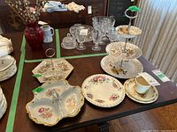 Table display showing multiple decorative plates, a 3-tier serving stand, sectional trays, and Bunnykins cup and saucer
