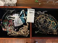 Two trays containing assorted costume jewellery including necklaces, chains, pendants, and bracelets. Pieces are multi-colored with metal, glass, and plastic beads.
