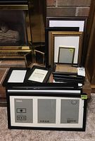 Lot of various size photo frames stacked near fireplace, includes single and multi-photo frames with several IKEA Ribba frames visible.