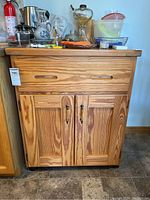 Front view of the wooden kitchen island showing drawer and cupboard doors with visible wood grain and metal handles.