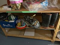 Shelf showing assortment of sports balls, frisbees, snowshoes, rubber boots and other gear