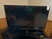 Front view of Toshiba 49-inch TV showing remote on stand, TV cabinet not included.