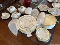 Photo showing grouped Westbury china plates, cups, and saucers with soft fabric storage cases on a wooden table.