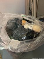 Plastic bag open showing multiple yarn skeins in various colors including black and grey