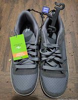 Front view of gray men's athletic shoes with laces and size tag 11 attached to hanger, showing new condition and retail tag.