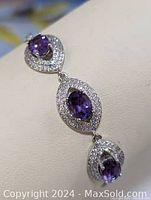 Close-up photo showing the teardrop-shaped silver settings holding faceted oval amethyst stones surrounded by cubic zirconia stones.