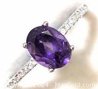 Close-up image showing oval purple amethyst center stone set in sterling silver with CZ stones on band.