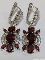 Close-up photo of a pair of sterling silver earrings with multiple garnet stones and cubic zirconia accents.