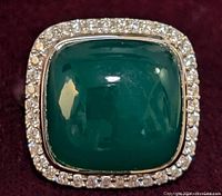 Close-up photo of the top of the ring showing square green onyx cabochon stone surrounded by a halo of clear stones on sterling silver setting.