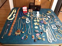 Entire lot laid out on table showing necklaces, brooches, earrings, boxes and belt