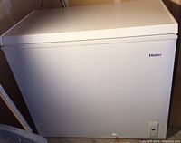 Haier white chest freezer with control switch on front panel.