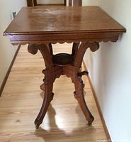 Front angled view showing the full table, carved legs with scroll details, and casters.