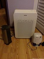 Three appliances on the floor: Winix air purifier in center, black Seville fan heater on left, ProBreeze small dehumidifier on right.