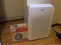 Full view of Winix air purifier next to boxed small fan