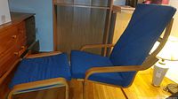 Blue Ikea POANG footstool alongside matching chair with blue cushions and light wood frames.
