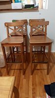 Four wooden bar stools grouped together showing overall design and set count