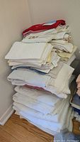 Stack of assorted towels and facecloths folded and piled in corner.