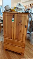 Front view of pine cabinet dresser with two doors and two drawers, top surface holding various hats.
