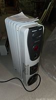 Full view of Kenwood EW0507TK oil filled radiator heater with attached power cord and instruction manual on top.