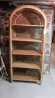 Front view of rattan shelf unit showing five shelves and arched top