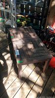 Three separate solid wood patio side tables, weathered condition, rectangular and square shapes, shown on wooden deck and surrounded by various outdoor tools and items.