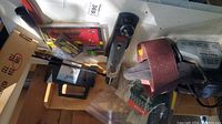 Overview of lots including metal hand plane, staple tool in original packaging, and Black & Decker belt sander with sanding belt.