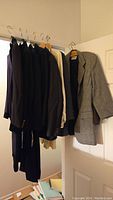 Multiple women's blazers and jackets hung on hangers in assorted colors including black, navy, gray, and beige, showing various sizes and styles.