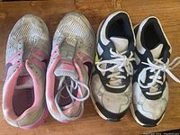 Top view of both pairs of Nike women's sneakers, one white with pink accents, one black and white.