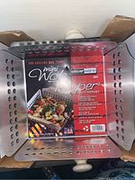 Top-down view of the square aluminum grill basket showing internal label and white handles